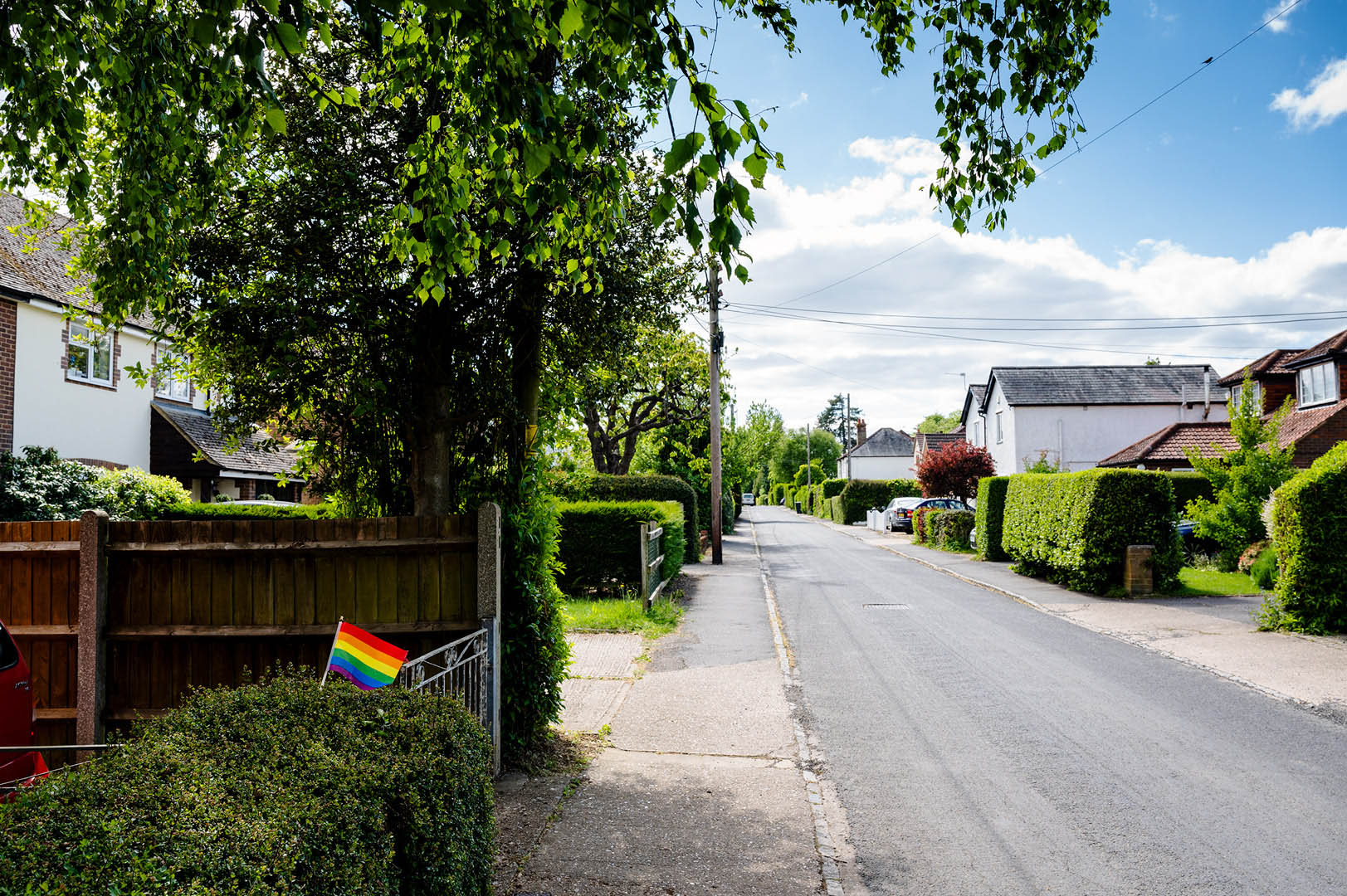 Rainbow flag in hedge on deserted street in Lockdown