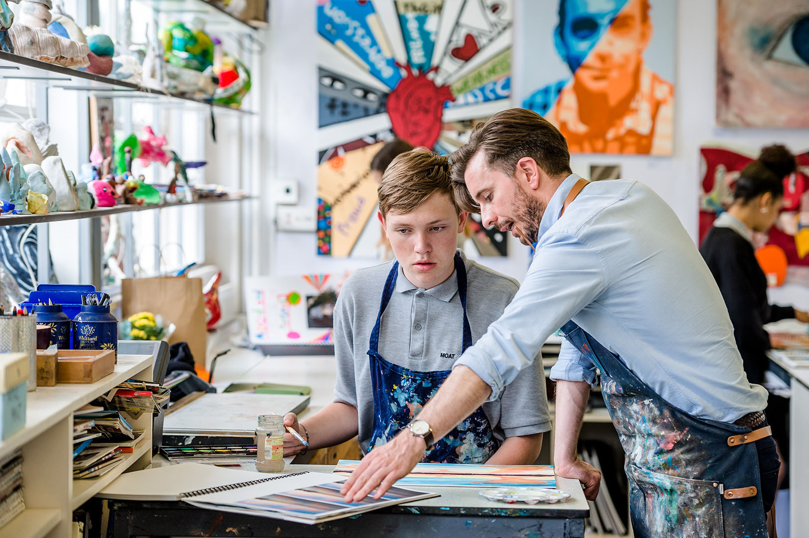 Teenage schoolboy with teacher discussing work in Art Class