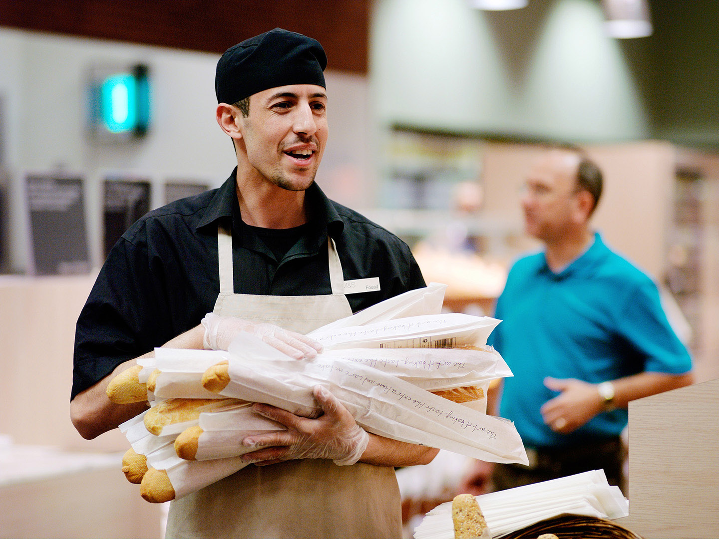 Man at work carrying Baguettes in Retail setting