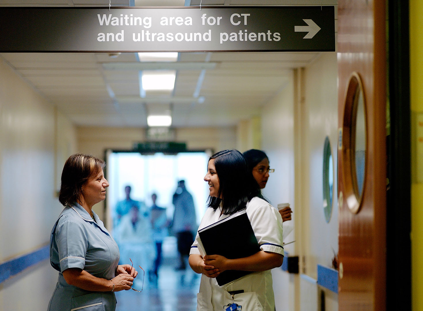 Nurse in discussion with Radiographer in hospital corridor