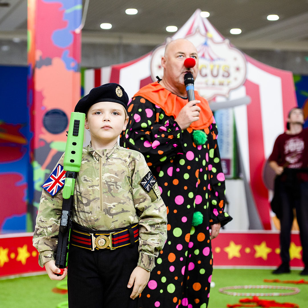Young Army Cadet showing drills with Clown announcer in the background