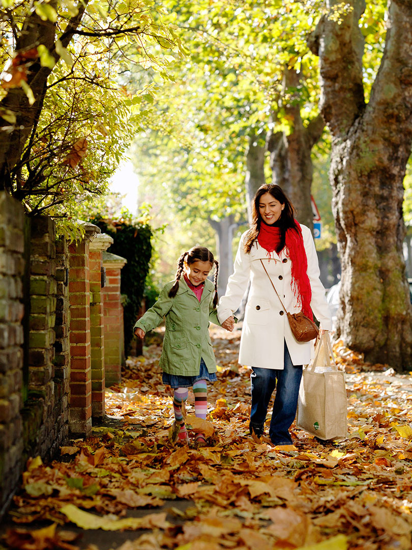 Asian Mother & Daughter skipping through autumn leaves