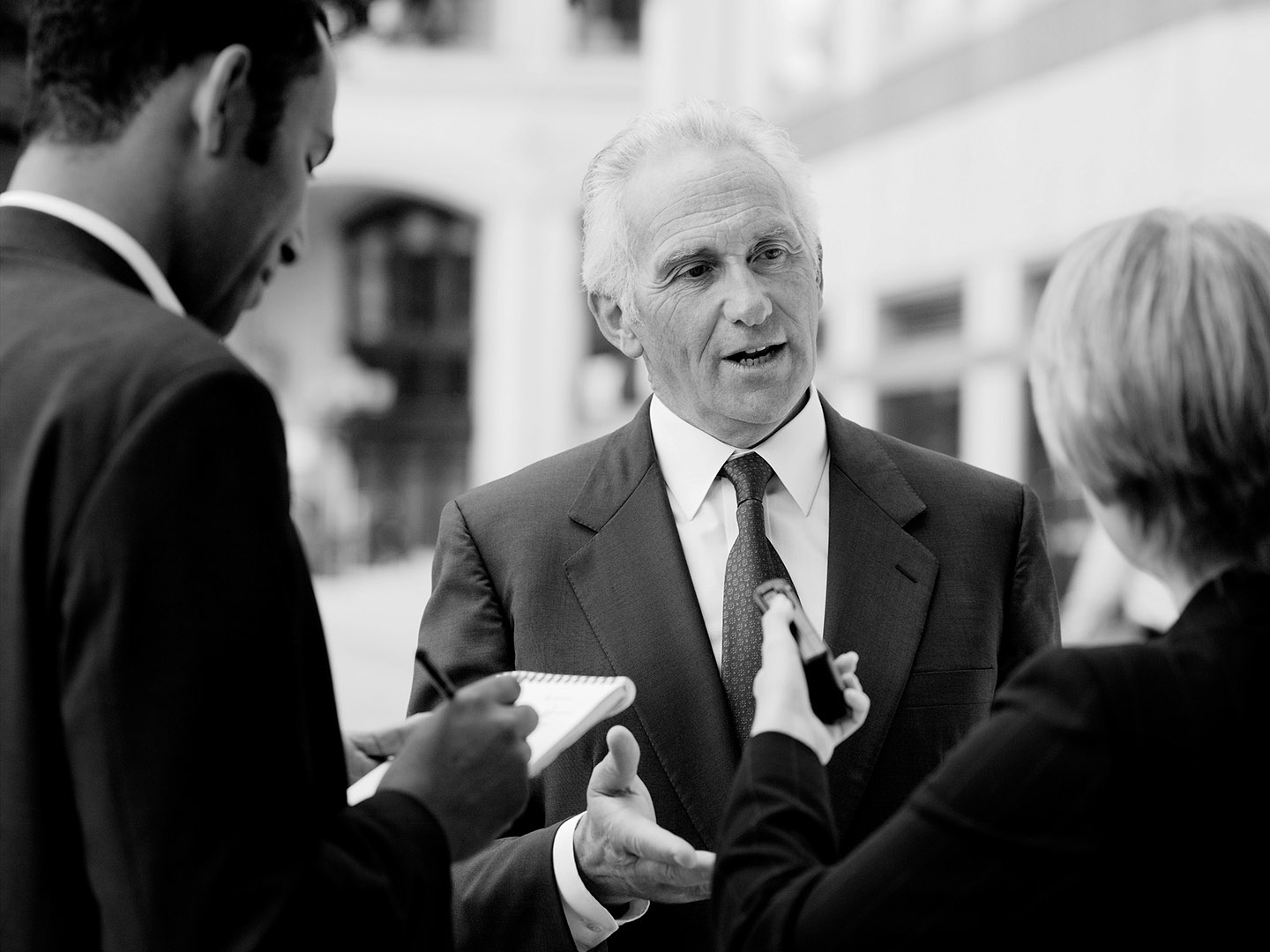 B&W reportage style shot of businessman being interviewed