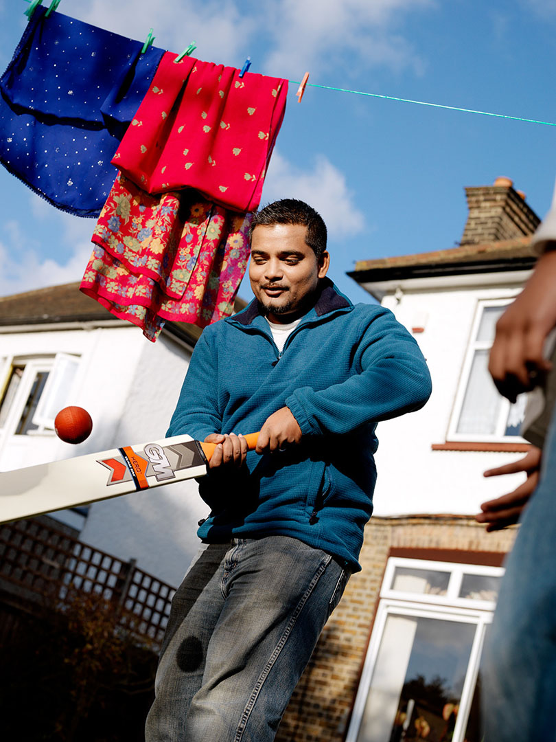 Asian father with cricket bat in garden setting
