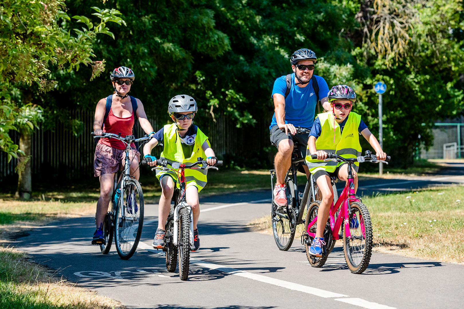Family of four riding bikes on cycle path in rural setting