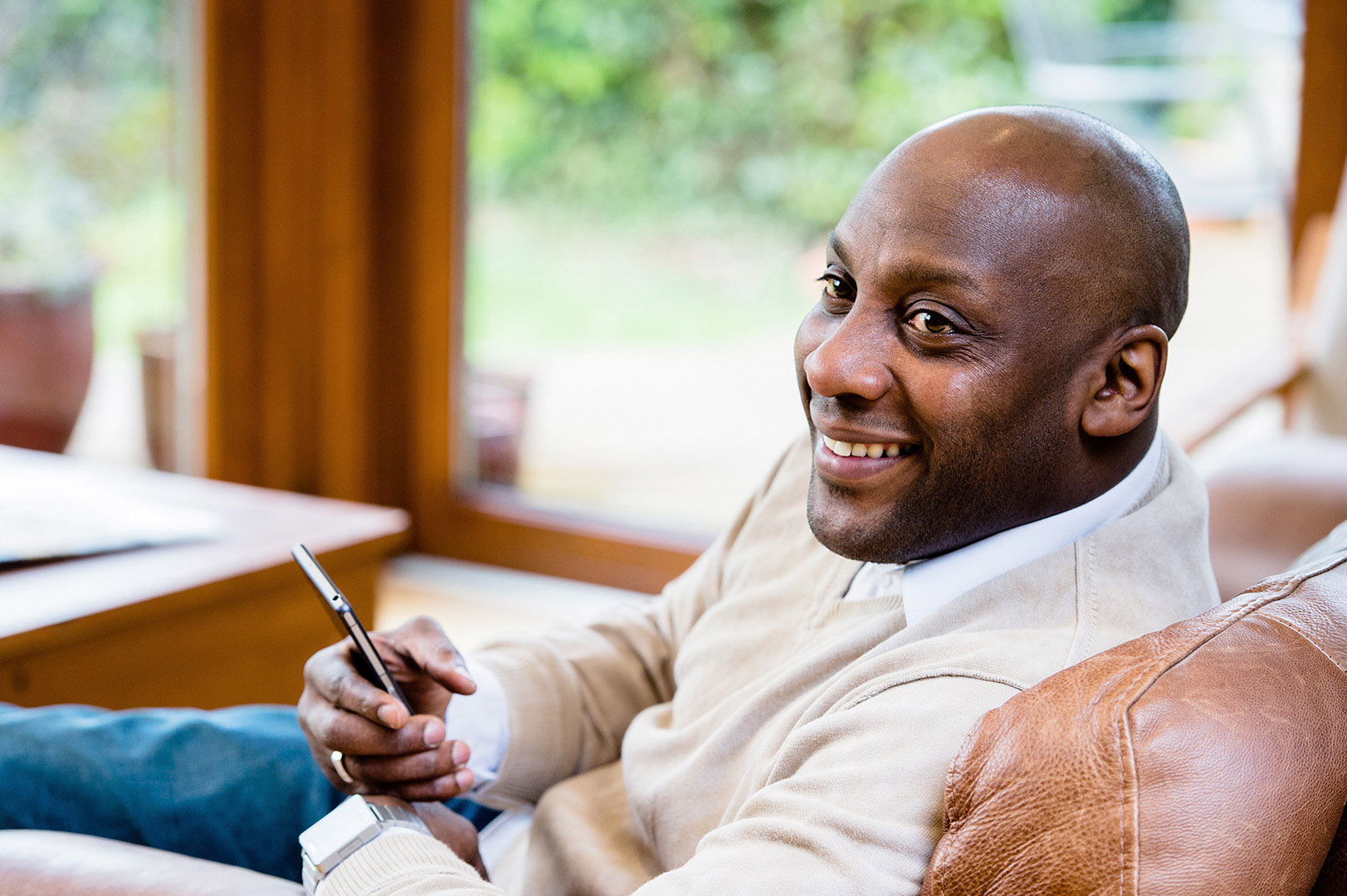 Black man in conversation off camera holding mobile phone