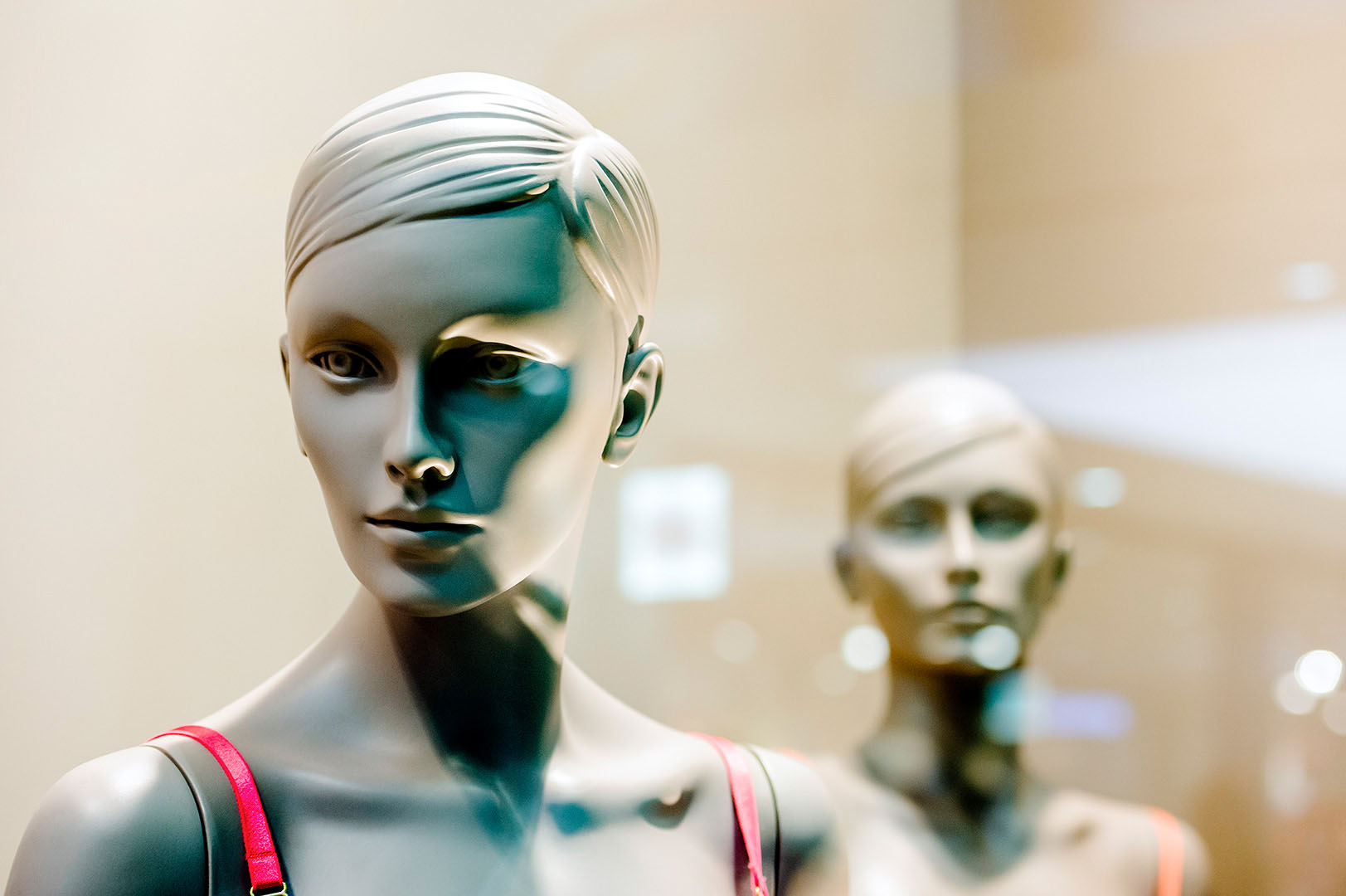 Mannequin staring out of frame whilst another looks on
