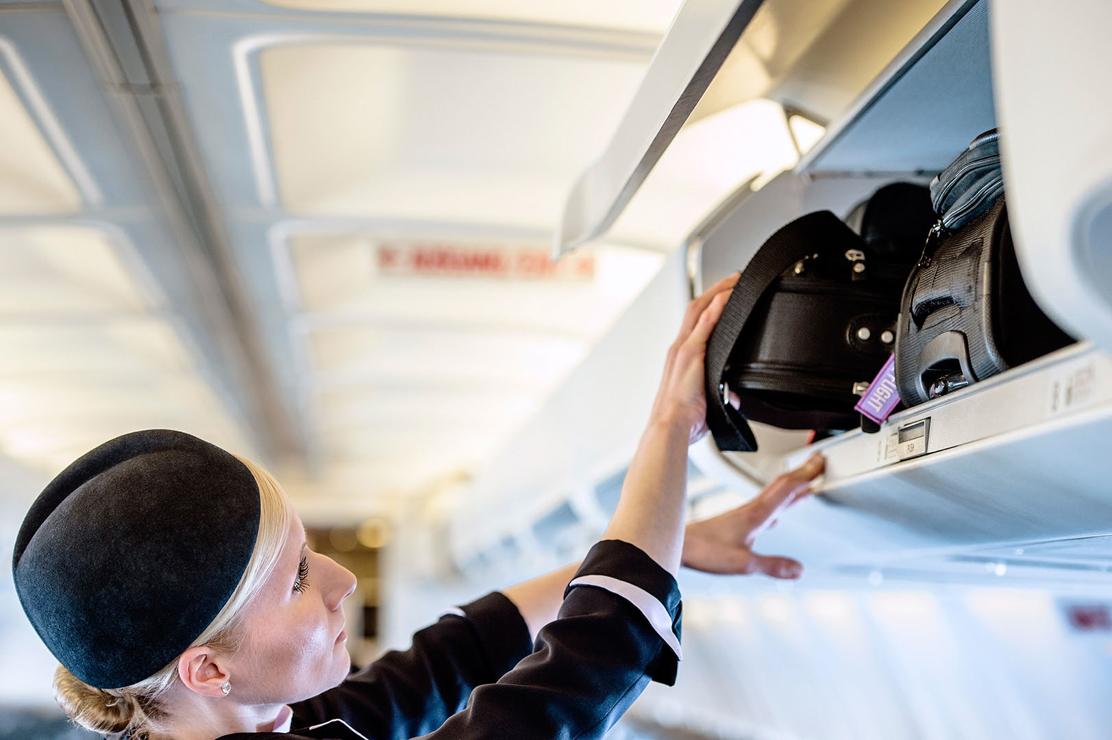 Air hostess putting bags in overhead locker