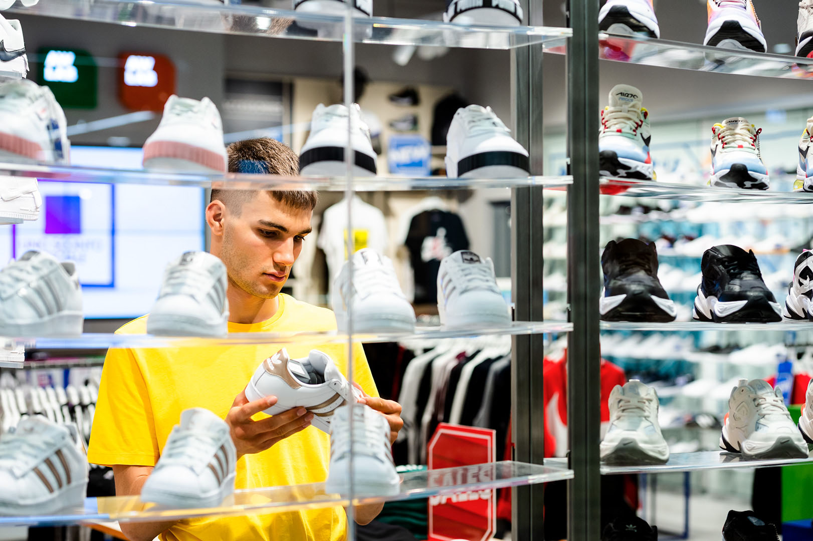 Young adult man looking at trainers in sport retail environment