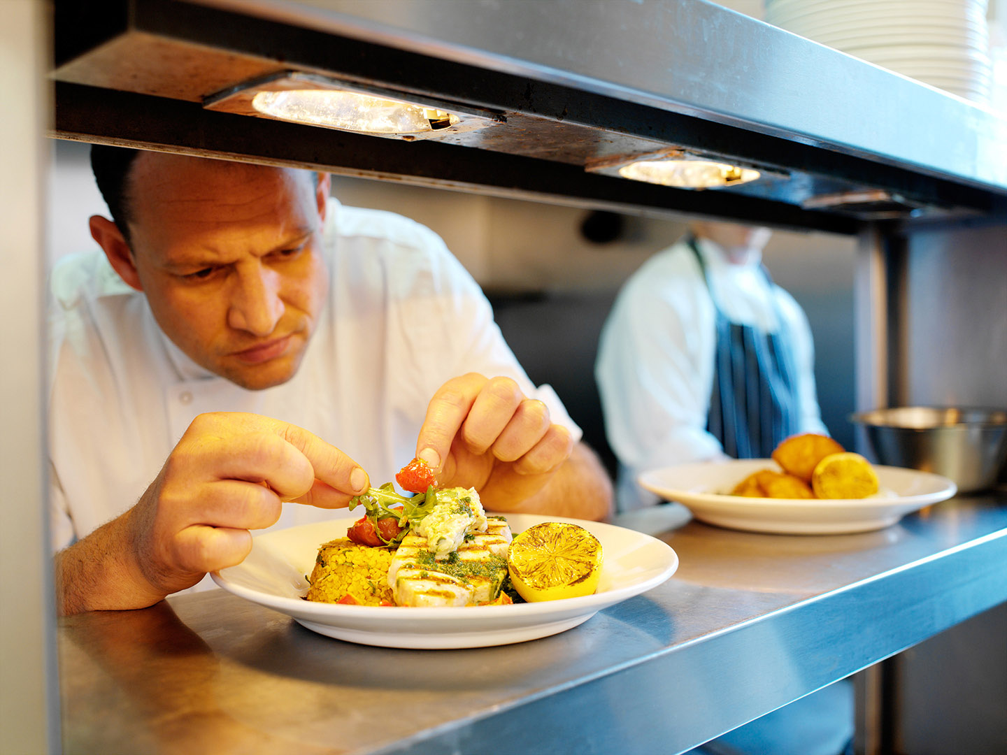 Chef putting finishing touches on plate of food before sevice