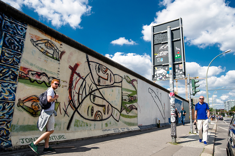 People walking alongside a section of the Berlin Wall at Eastside Gallery shot in wide angle