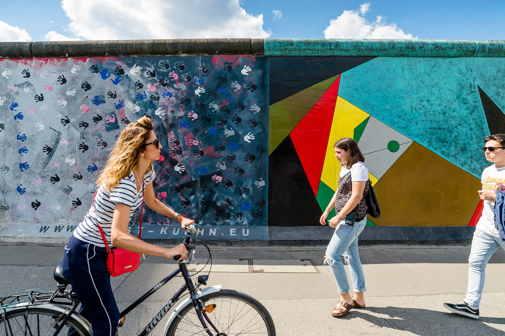 Woman cycling past secion of Berlin Wall