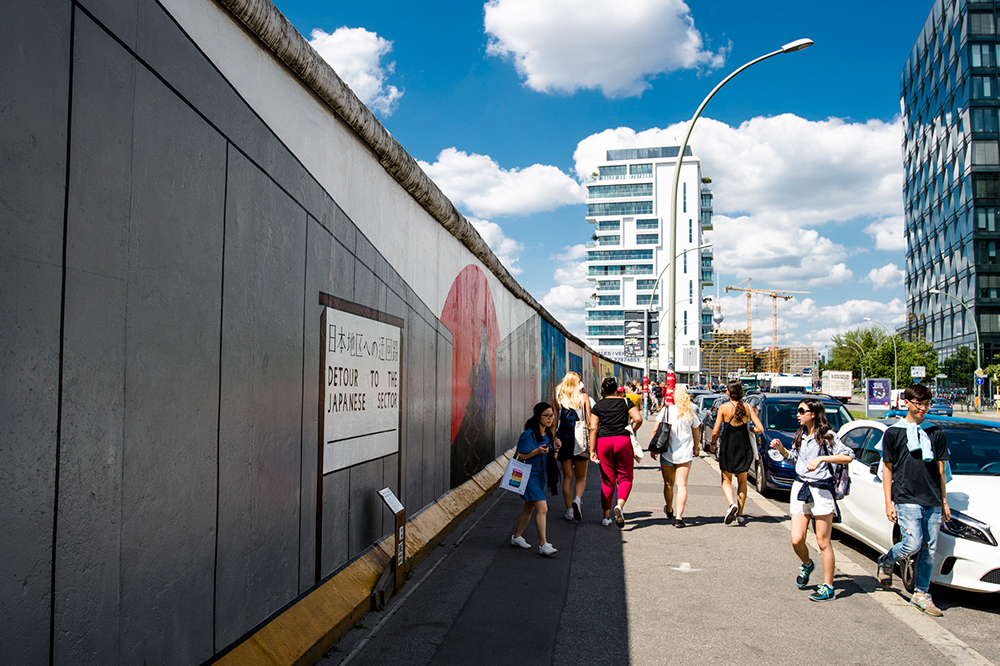 Tourists walking along a section of the Berlin Wall at Eastside Gallery