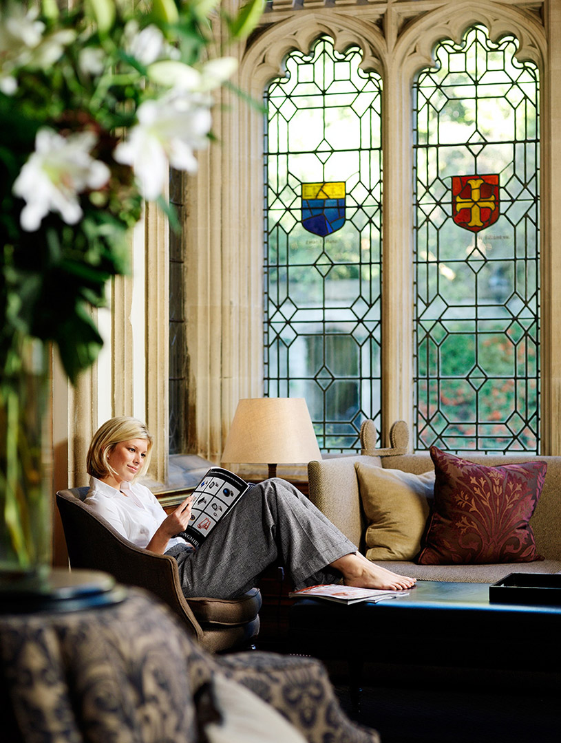 Woman in hotel setting relaxed and reading magazine