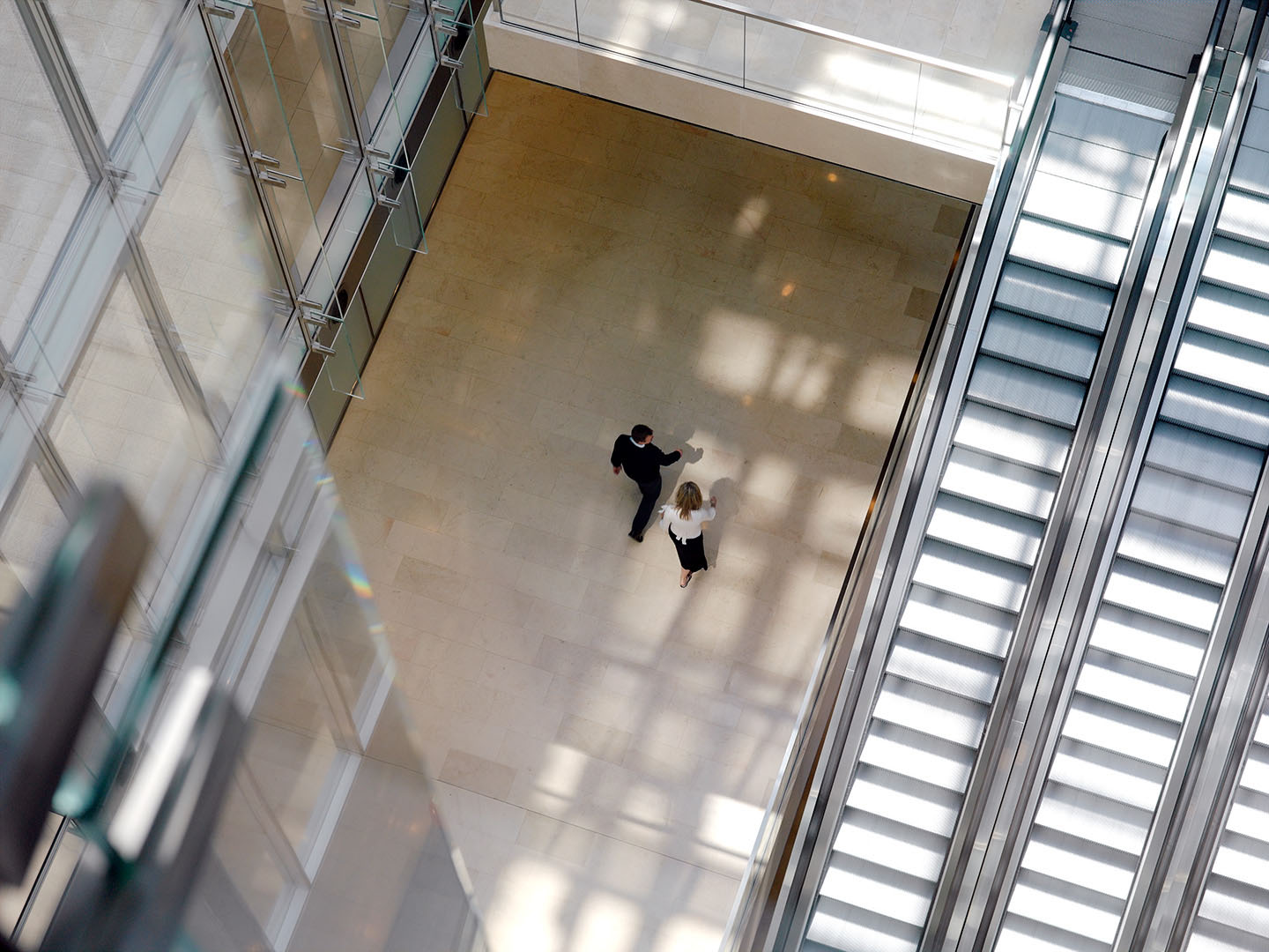Overhead shot of man and woman walking though the atrium of a corporate office building