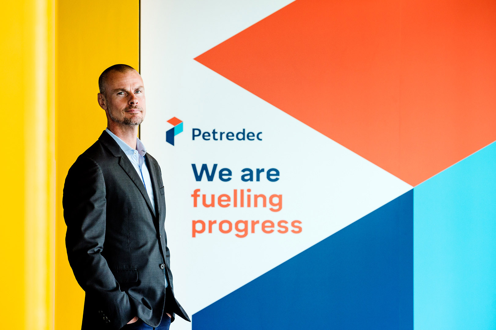 Director from the waist up in front of company branding