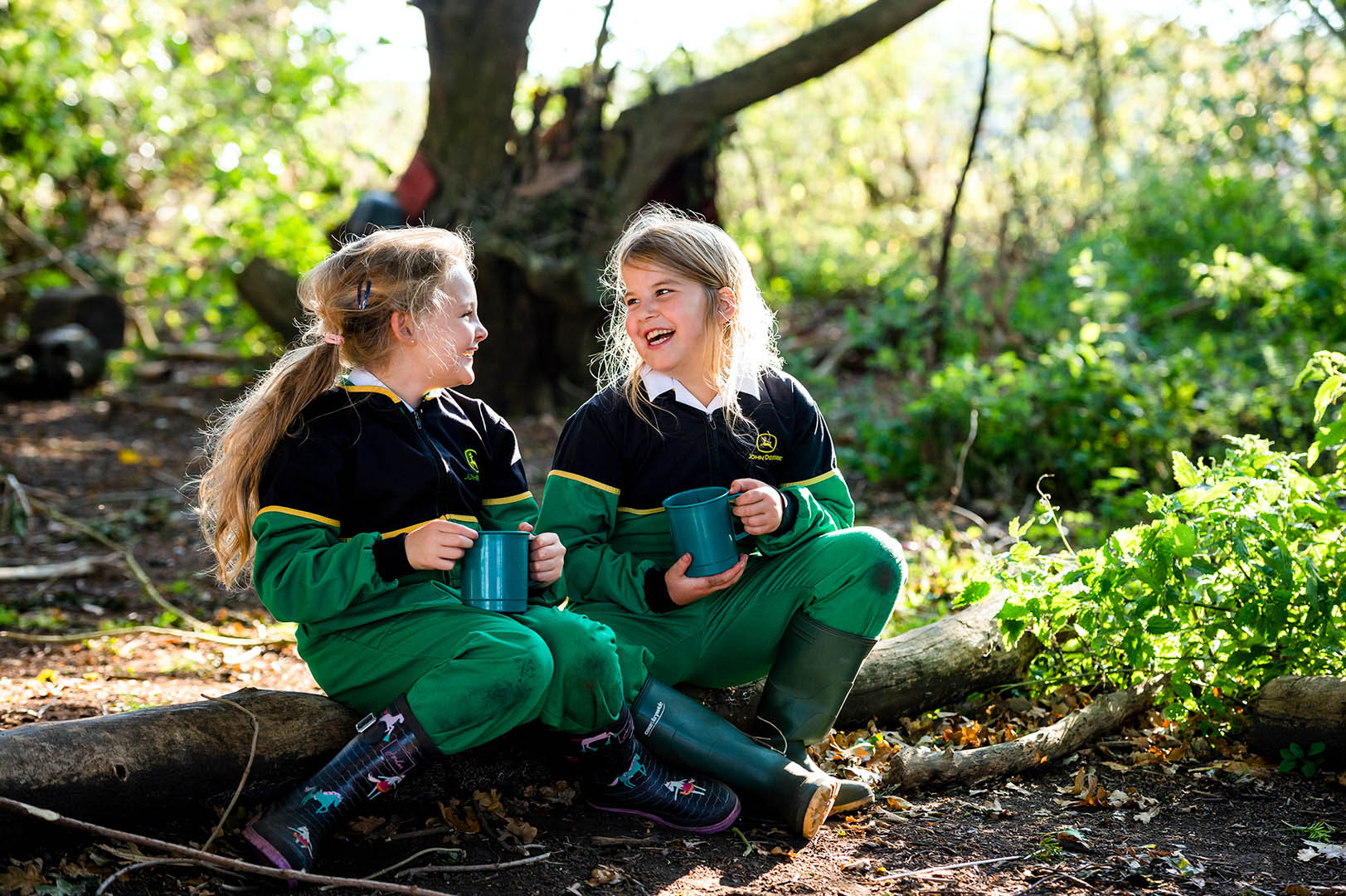 Two young female students laughing in woods at Forest School