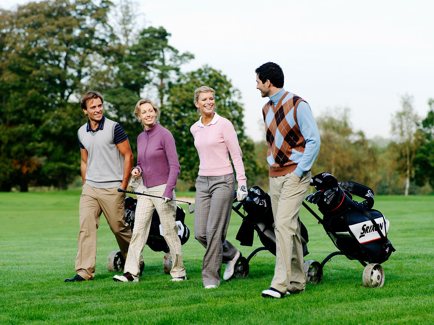 Mixed fourball of golfers walking down fairway