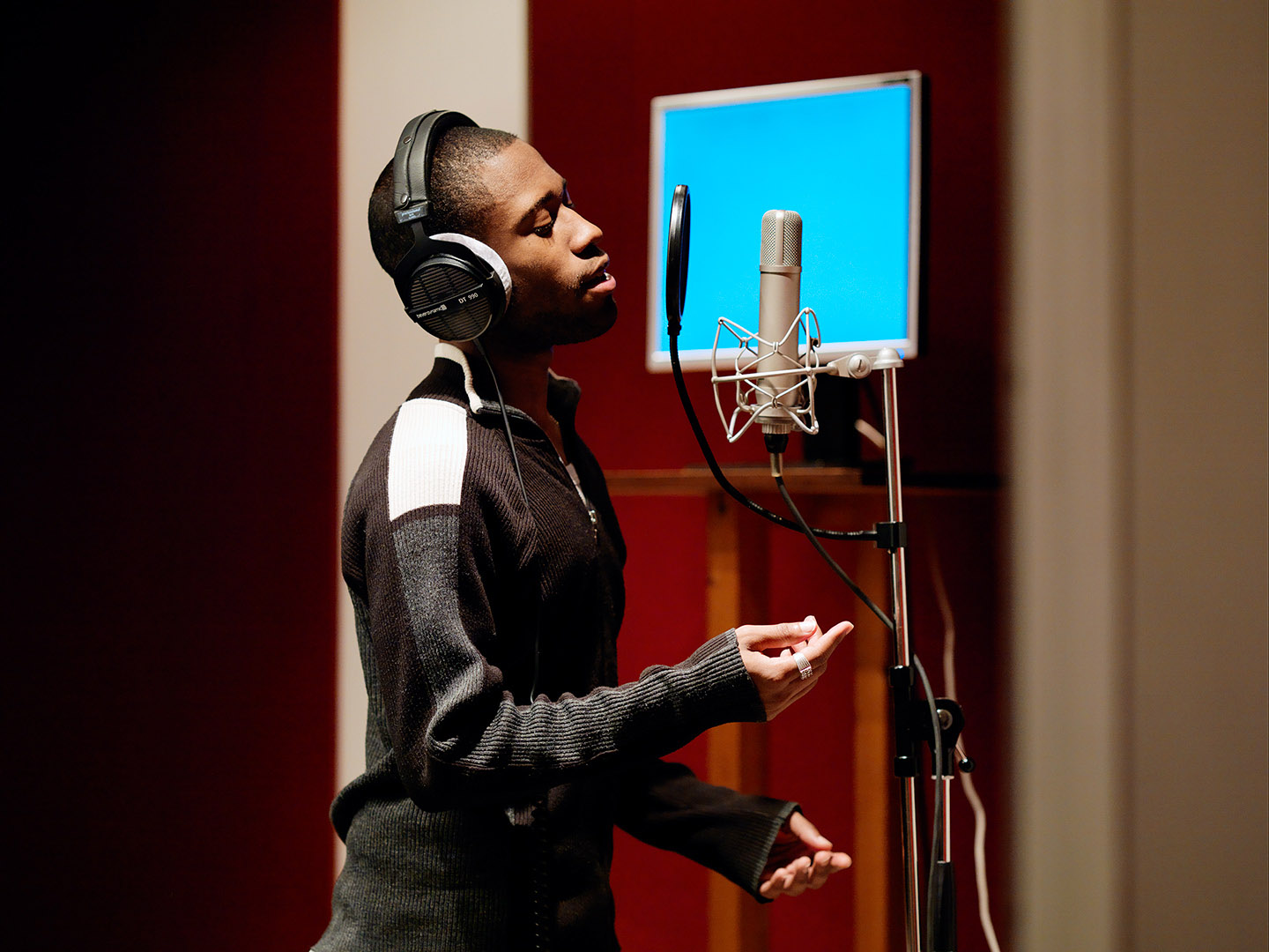 Black male music student in profile singing into recording microphone