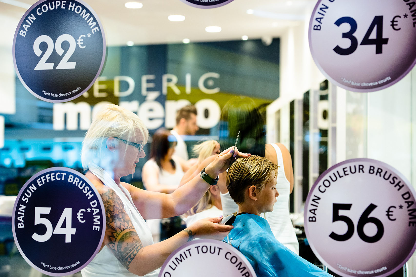Looking through window to young boy having his hair cut in French Salon
