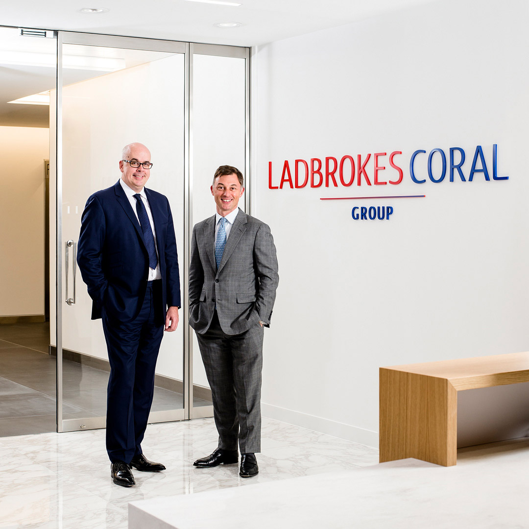 Portrait of two male directors in branded reception area