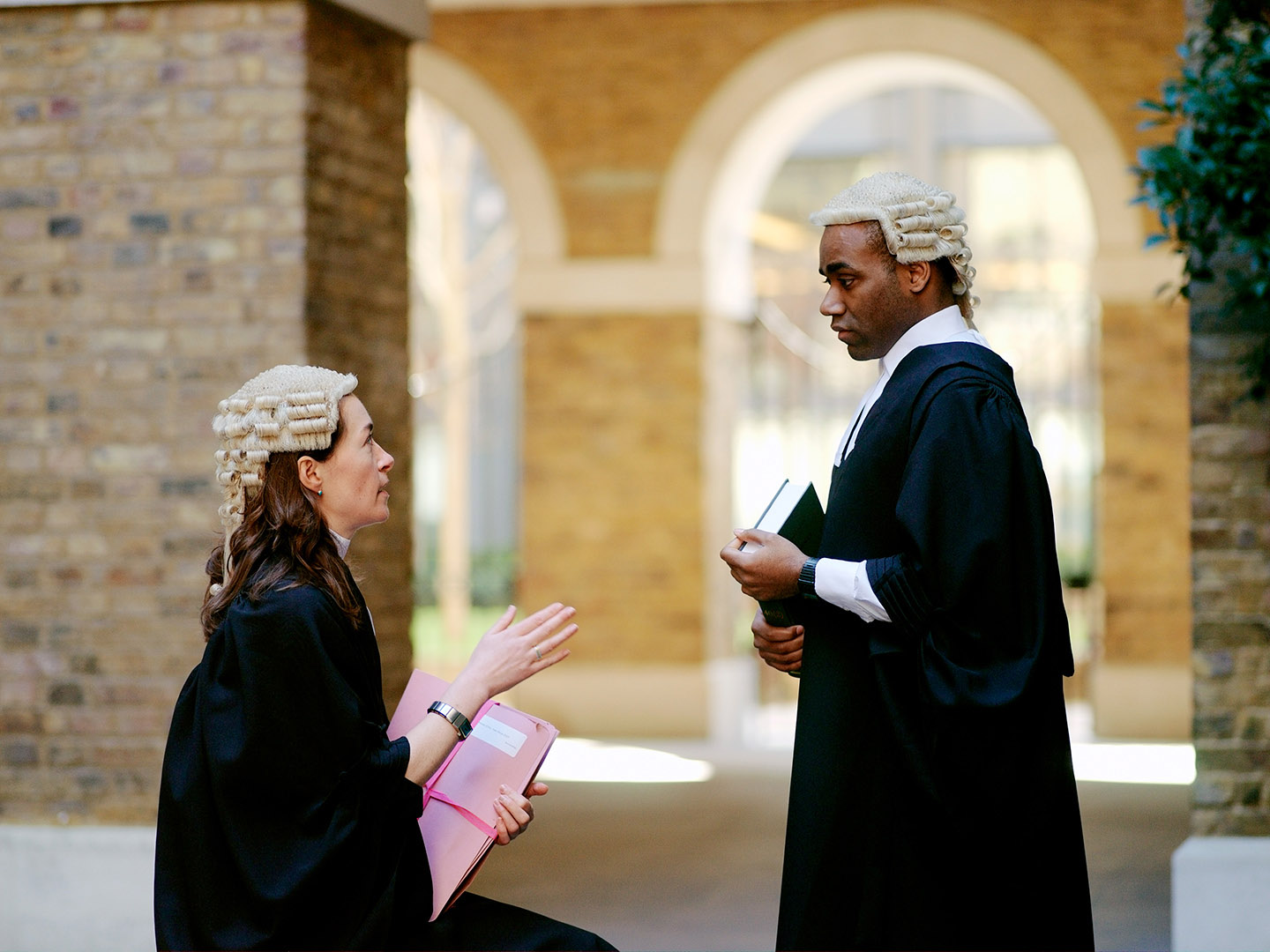 Two barristers, male and female in discussion in courtyard