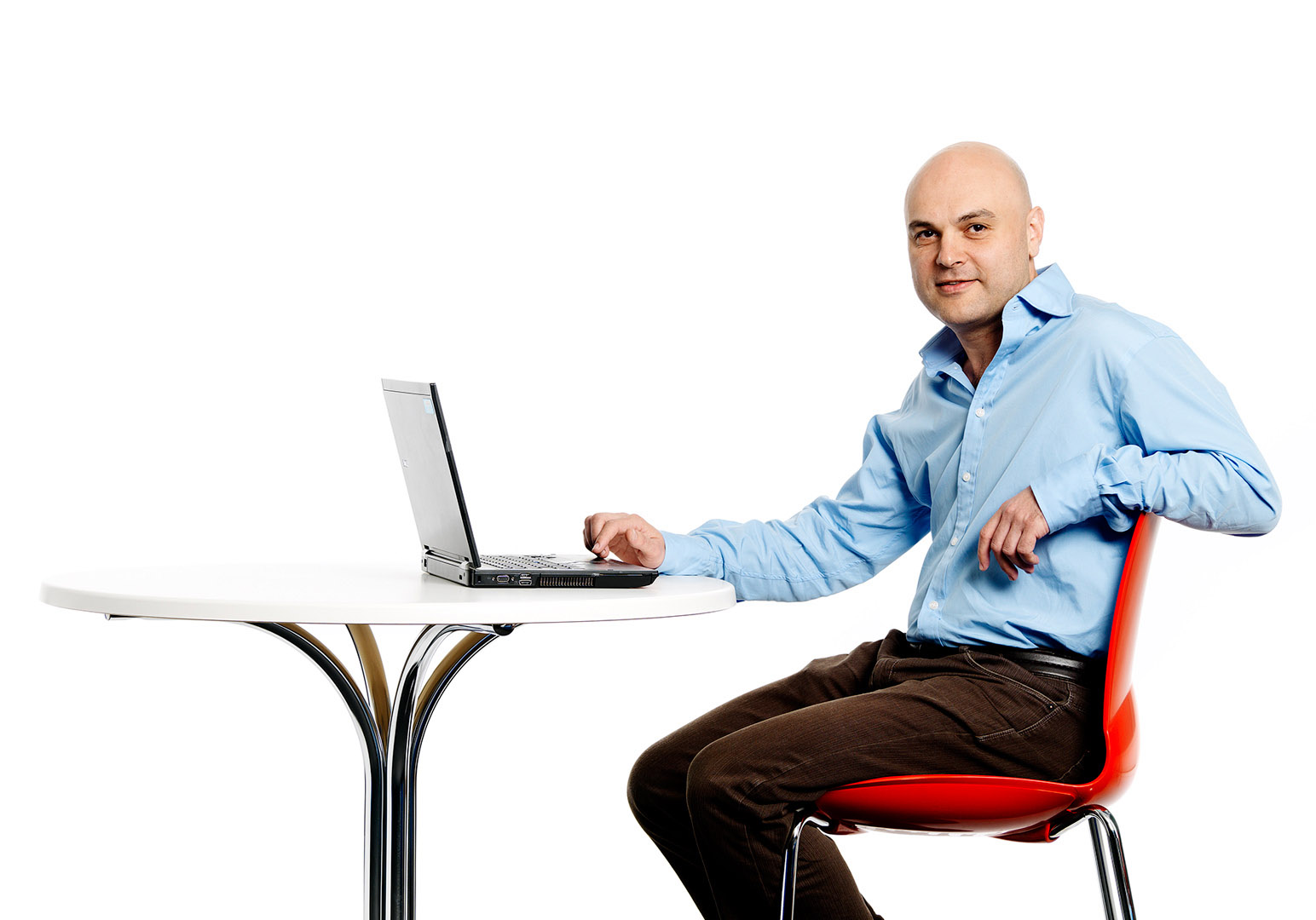 Cutout portrait of man with red chair round table and laptop
