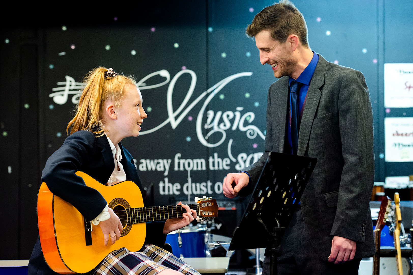 Young female student with guitar and Music teacher smiling in conversation