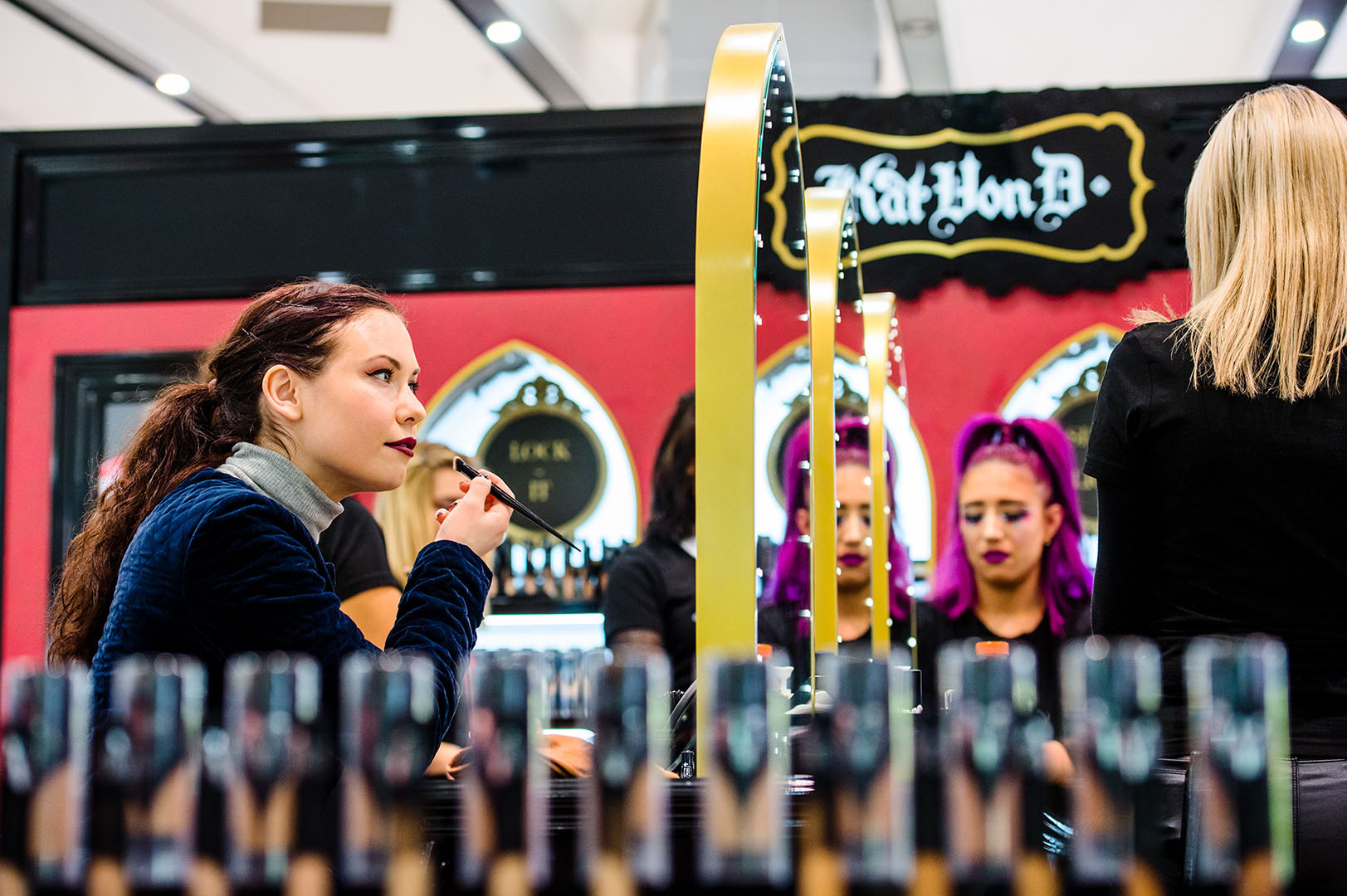 Woman applying her own make up looking at mirror in department store setting