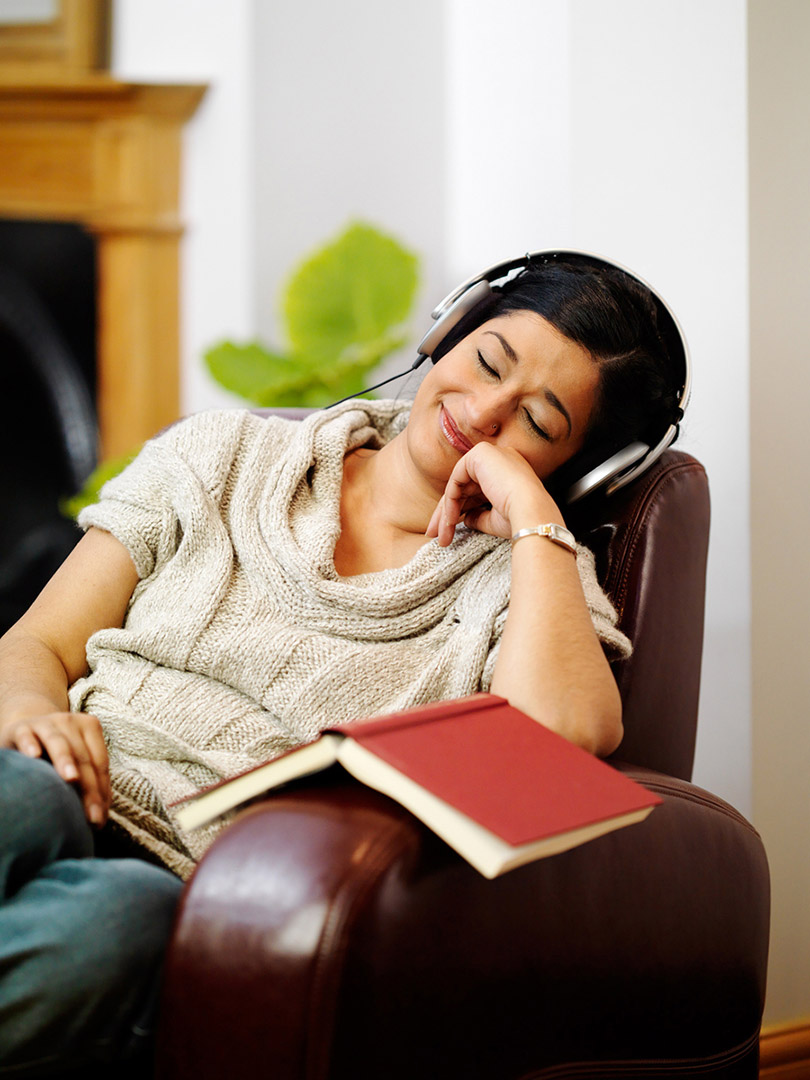 Asian woman deep in thought eyes closed smiling with headphones on