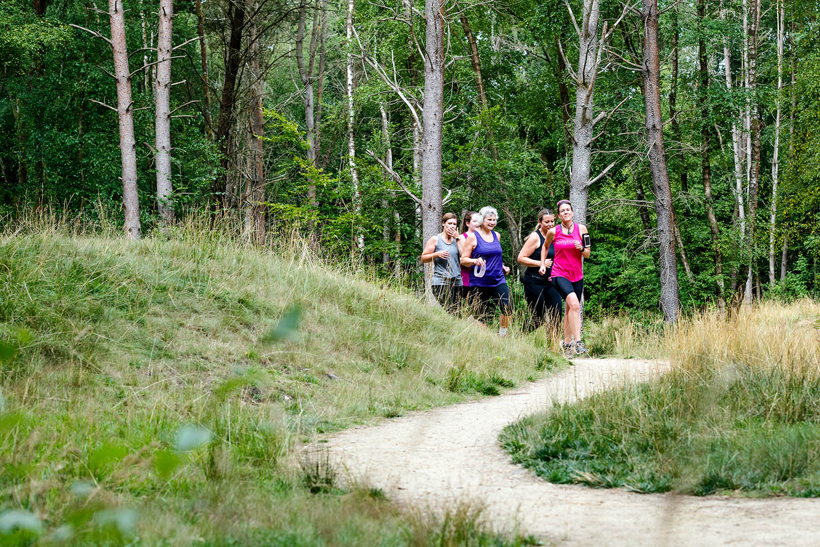 Group of female joggers coming onto an s bend in woodland setting