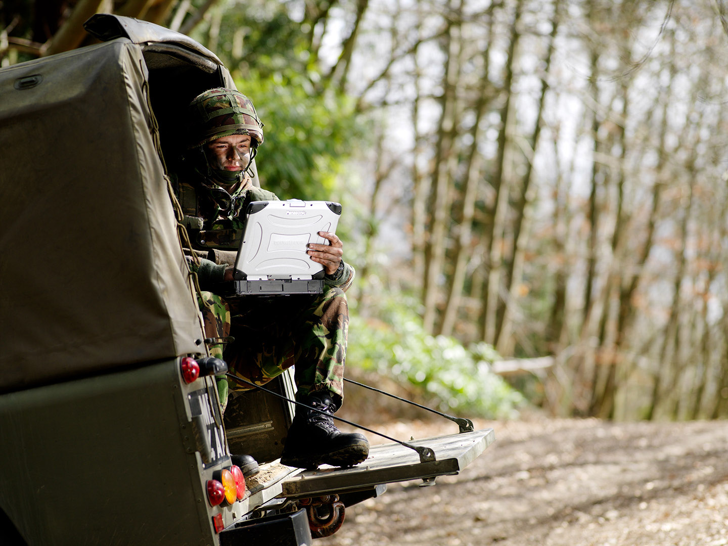 Soldier in the back of a covered vehicle with military grade laptop