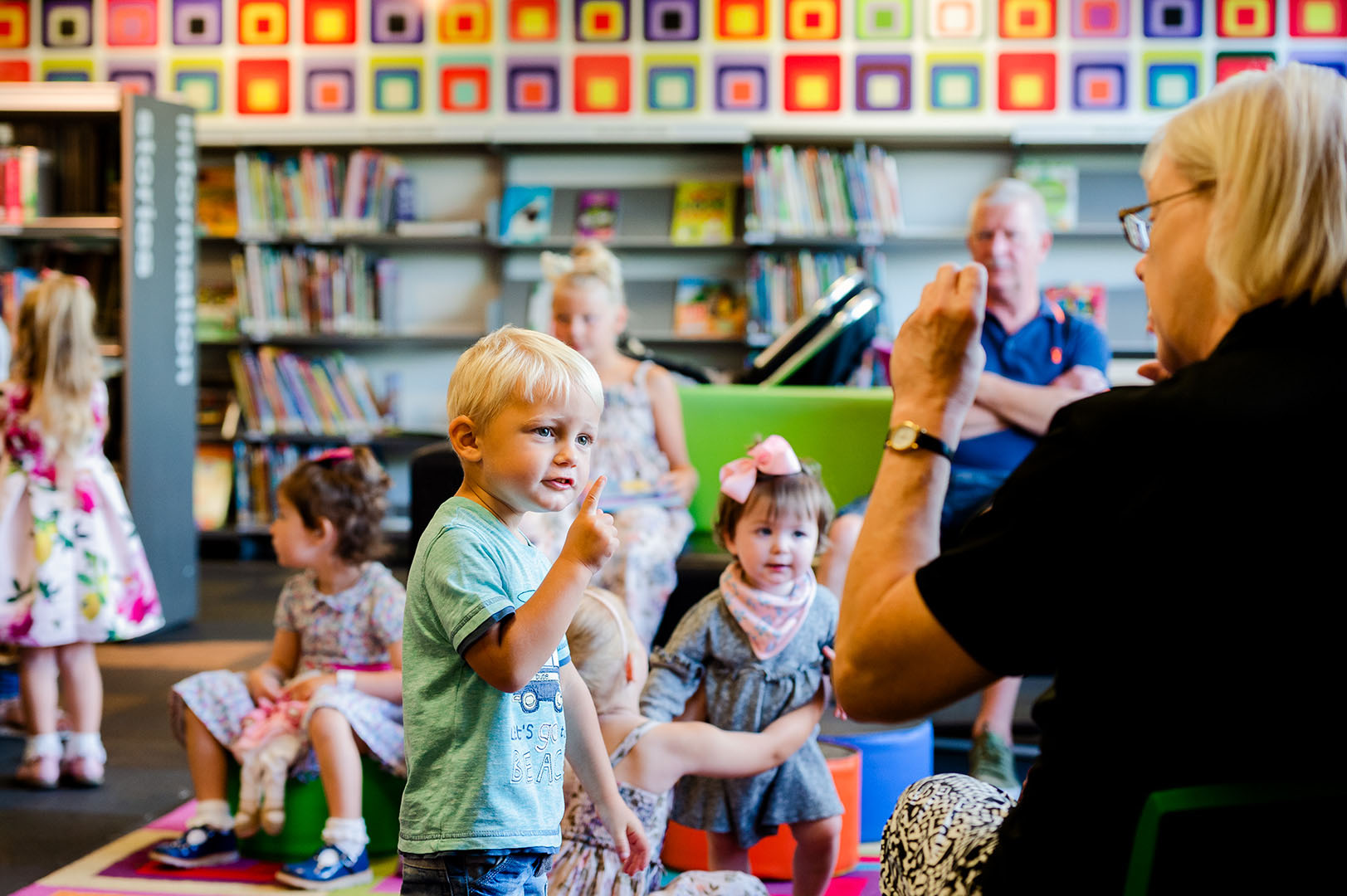 Young boy in conversation with teacher in library setting