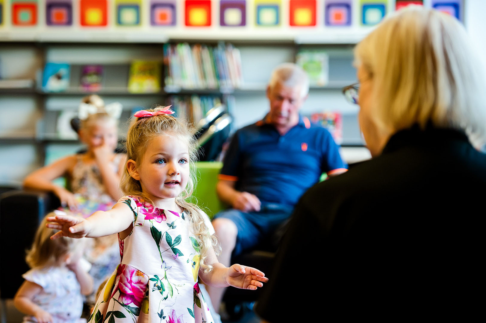 Young girl in conversation with teacher in library setting