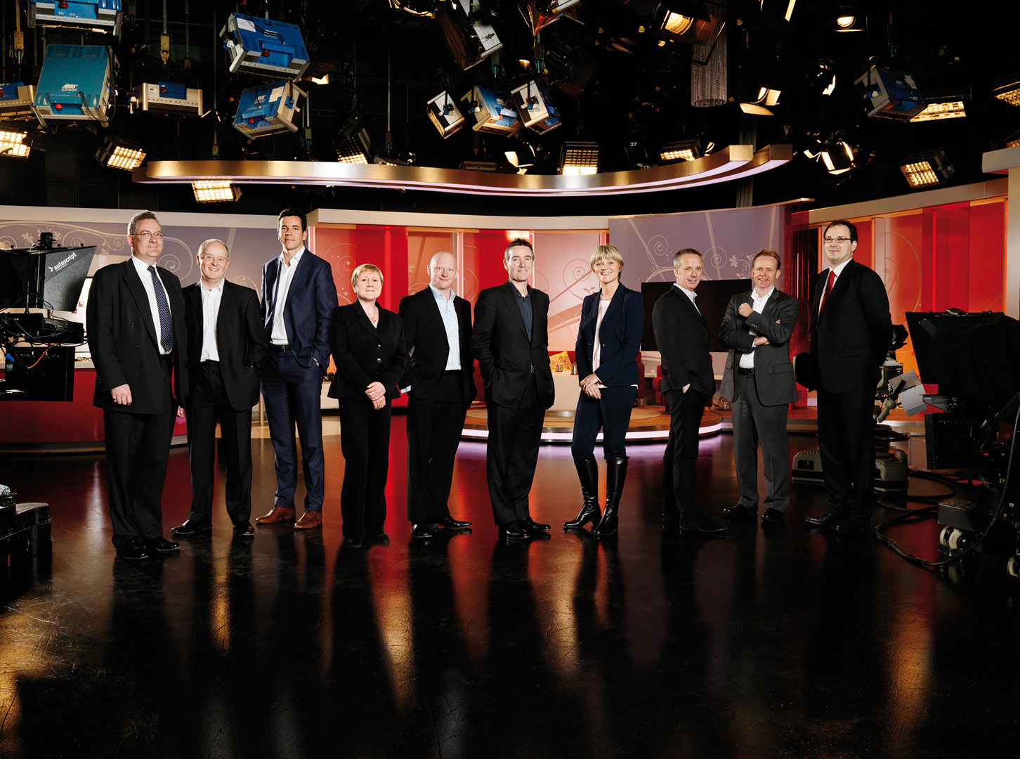 Management Group standing full length in front of TV Studio set