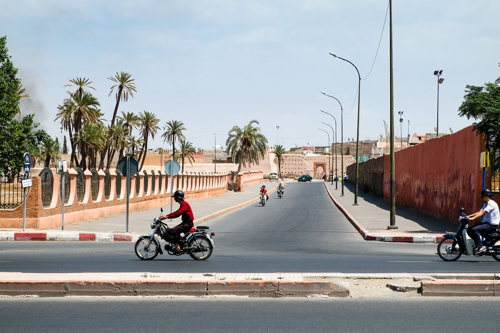 Wide Marrakech street scene with palm trees and scooters