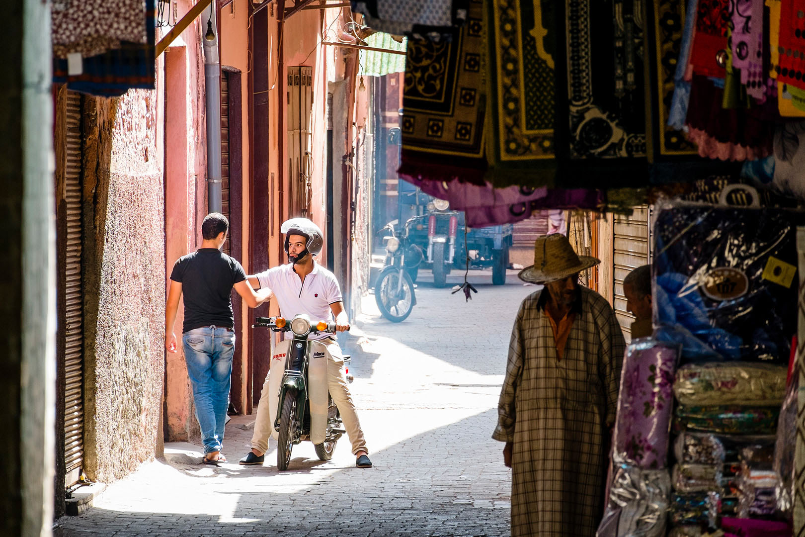 Conversation seated on a scooter in Marrakech Bazaar scene