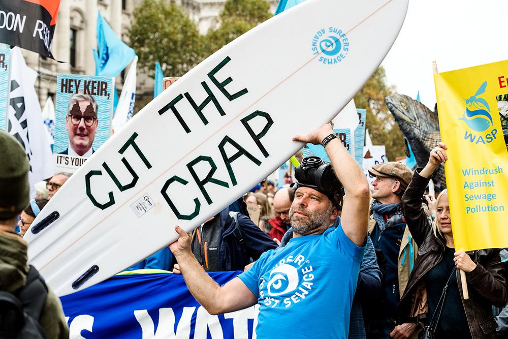 Slogan on surfboard held aloft at March for Clean Water in Westminster