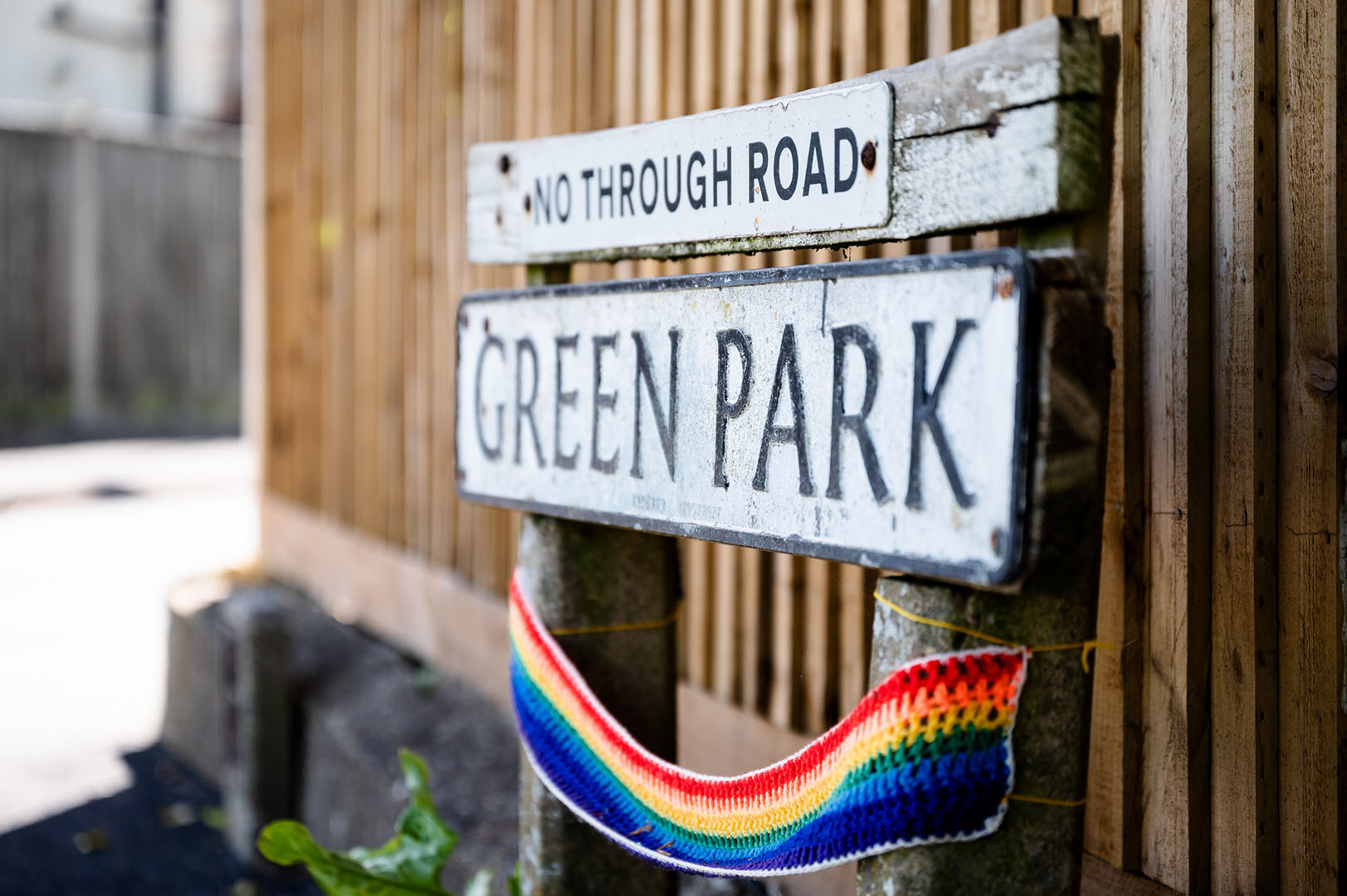Knitted rainbow scarf draped on roadsign during lockdown
