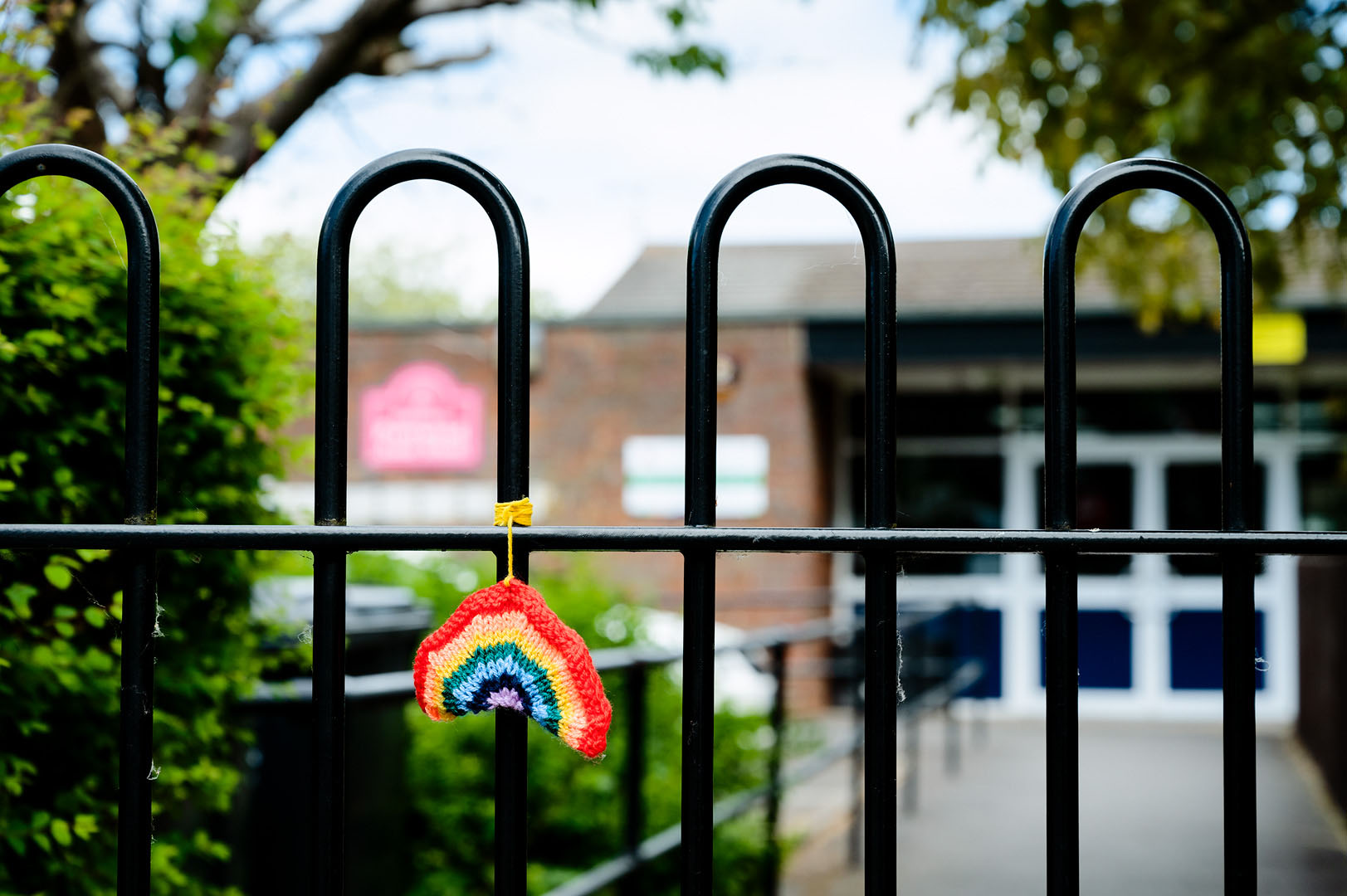 Knitted rainbow on locked school gate during lockdown