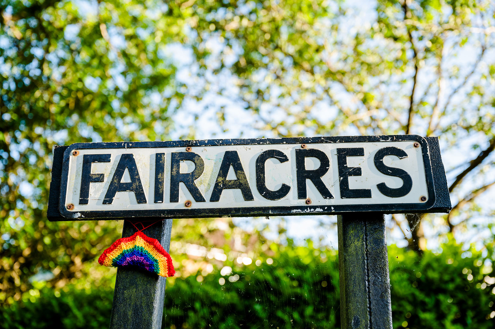 Knitted Rainbow on Sun lit Road Sign during Lockdown