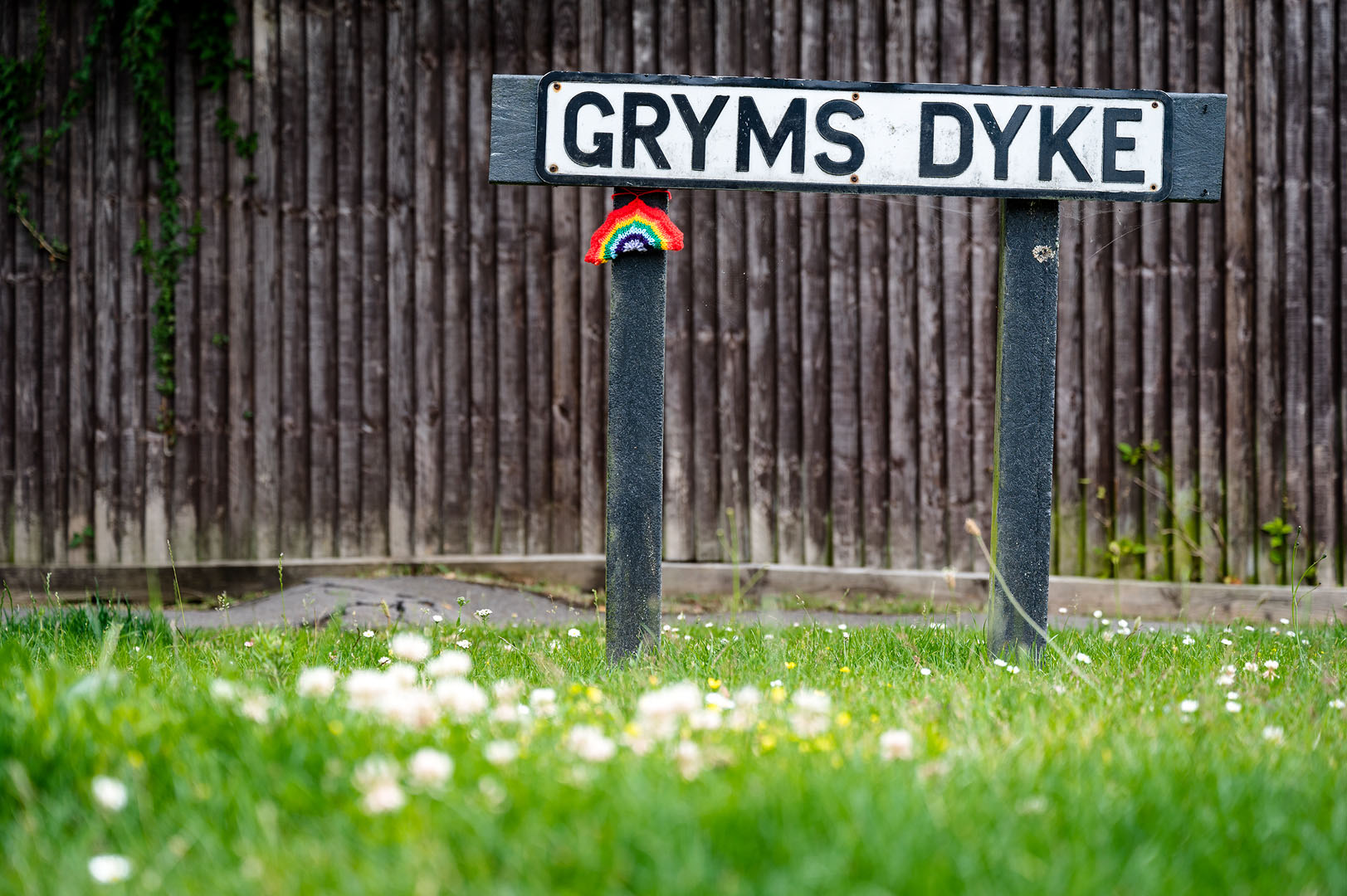 Knitted rainbow lights up otherwise mundane street sign during lockdown